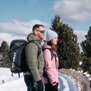 Couple hiking through the snowy mountains on a sunny winter day.