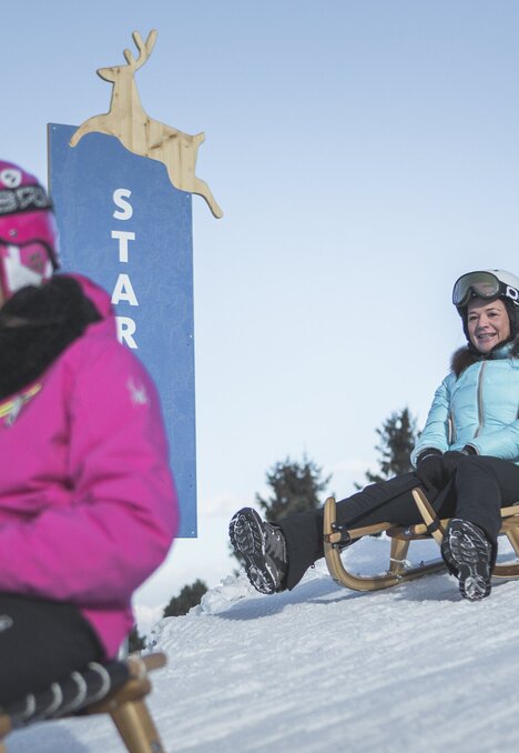 Bambini in slitta su una pista innevata in inverno a Brixen Südtirol.