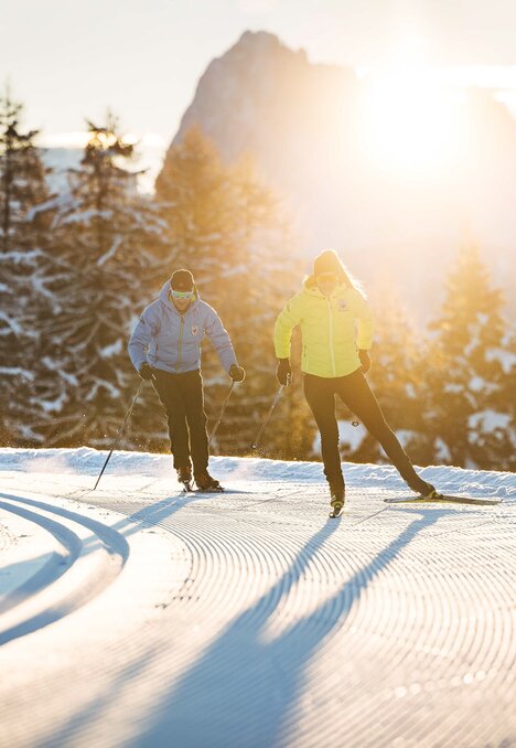Due persone praticano lo sci di fondo su un tracciato innevato all’alba a Brixen Südtirol.