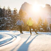 Twee mensen langlaufen over een besneeuwde route bij zonsopgang in Brixen Südtirol.