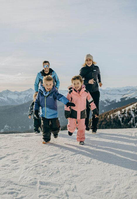 Familie läuft im frischen Schnee einen Hang am Berg hinauf.
