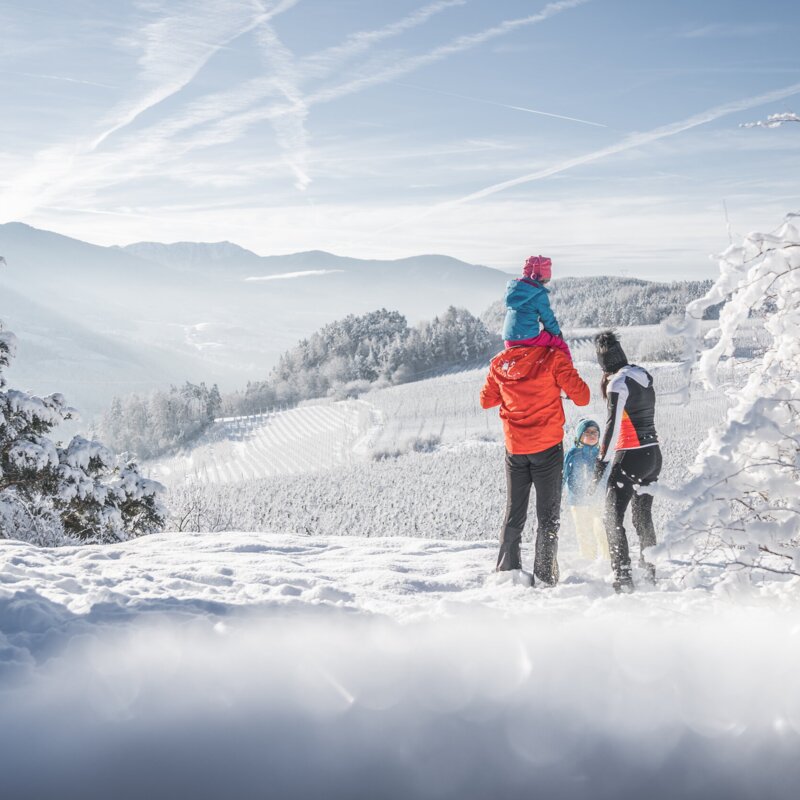 Famiglia nella neve fresca con vista sulle montagne invernali e sulla valle a Brixen Südtirol.