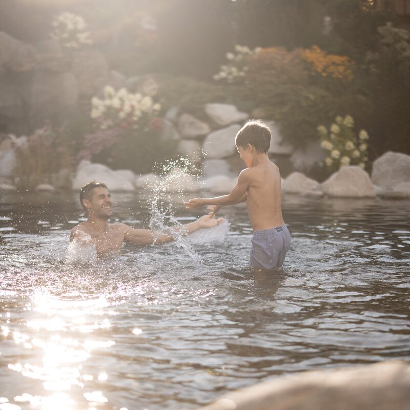 Padre e figlio giocano insieme in una piscina all’aperto illuminata dal sole