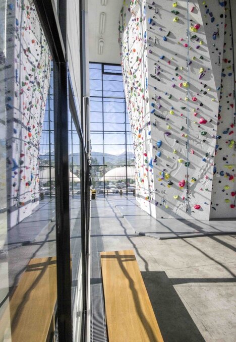 Parete da arrampicata indoor con ampia vetrata e vista sulle montagne