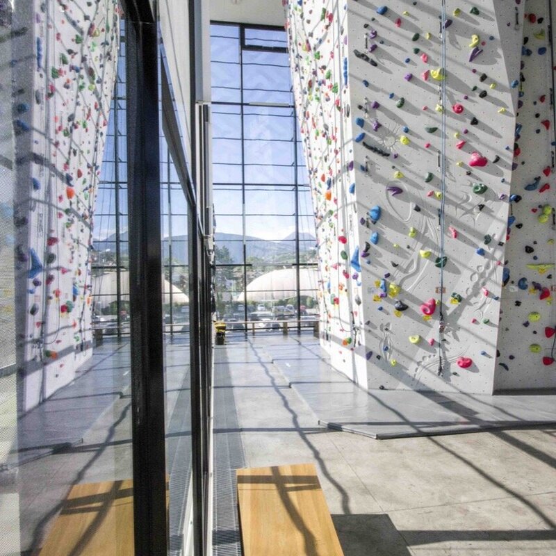 Indoor-Kletterwand mit großer Glasfront und Blick auf die Berge