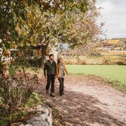 Coppia che cammina su un sentiero coperto di foglie nel paesaggio autunnale vicino a Brixen Südtirol.
