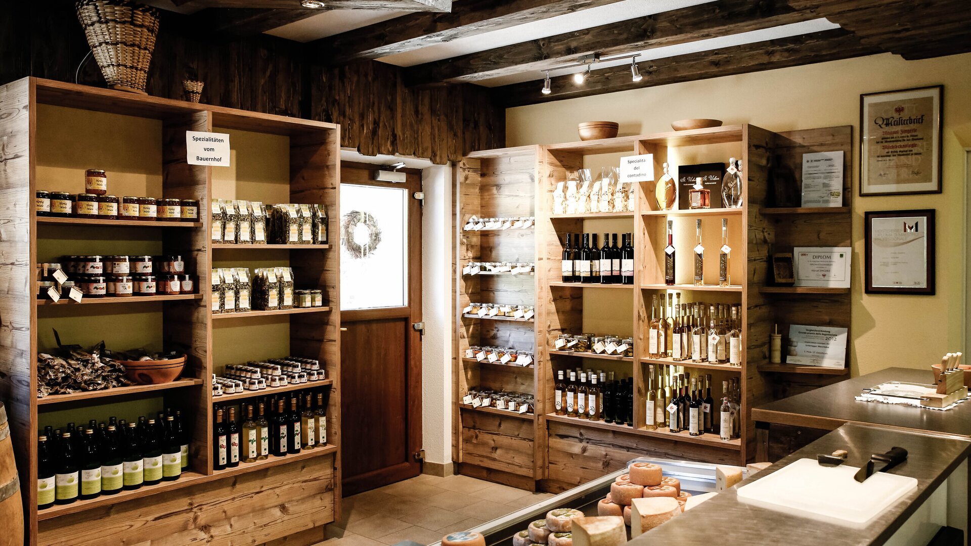 Interior of a rustic shop with shelves of regional products and cheese on the counter.