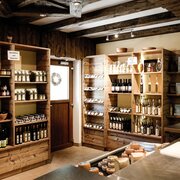 Interior of a rustic shop with shelves of regional products and cheese on the counter.
