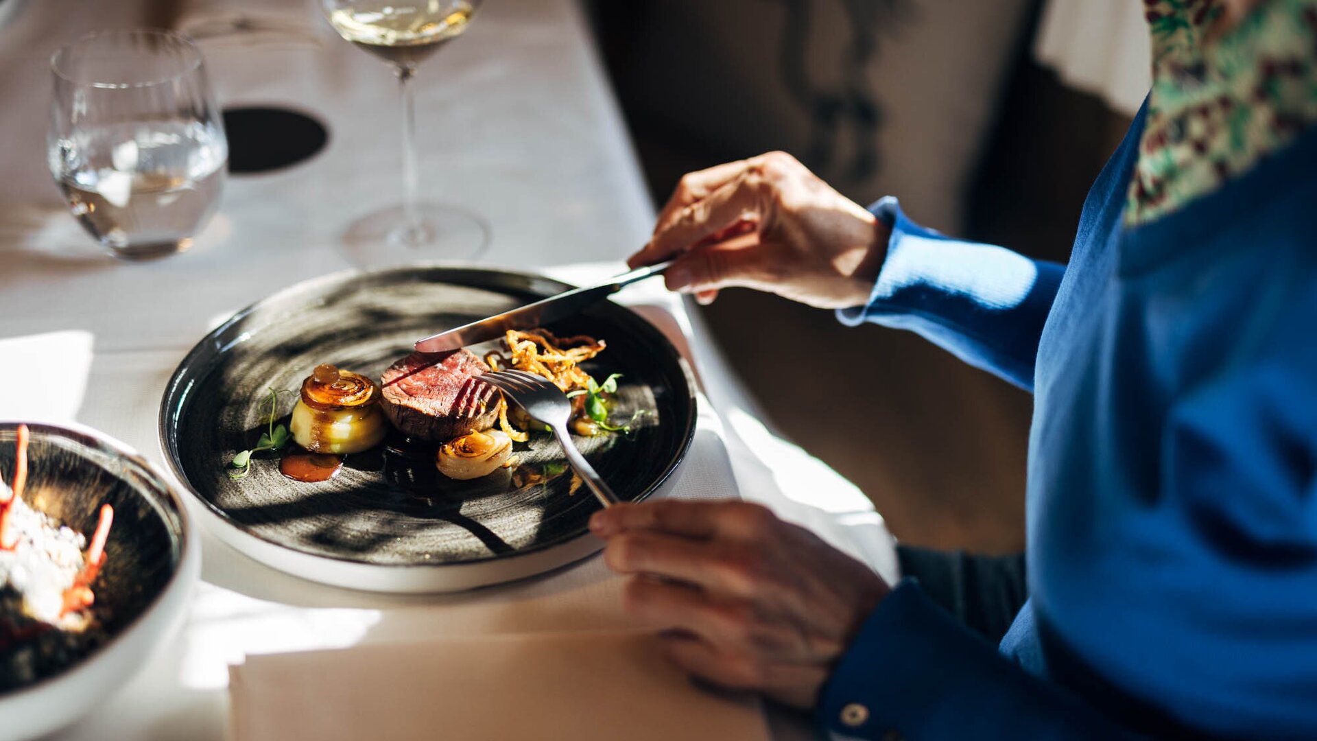 Guest enjoying a plated restaurant dish with wine glasses on the table