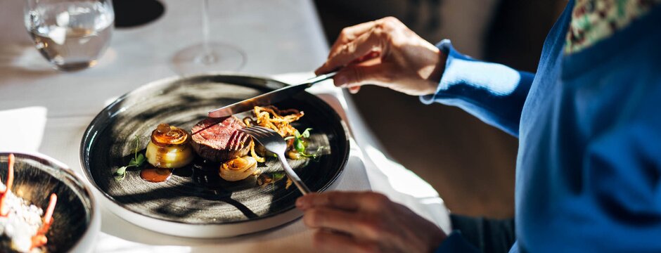 Guest enjoying a plated restaurant dish with wine glasses on the table