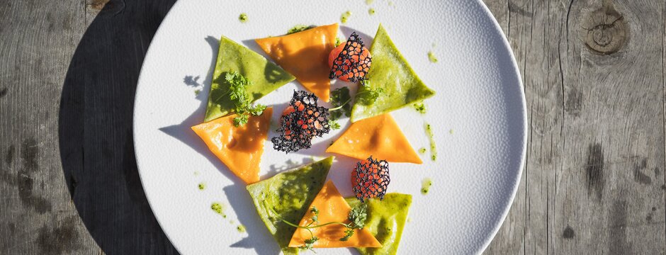 Bunte dreieckige Ravioli auf einem weißen Teller im Sonnenlicht