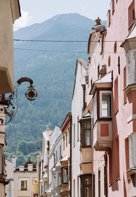 Vicolo stretto a Brixen Südtirol con facciate storiche e sfondo di montagna.