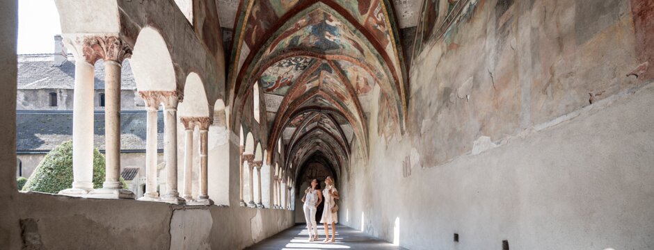 Corridoio del chiostro affrescato con archi a Brixen Südtirol, due persone camminano | © IDM Südtirol-Alto Adige/Alex Filz