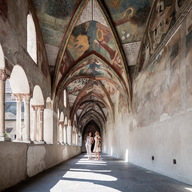 Corridoio del chiostro affrescato con archi a Brixen Südtirol, due persone camminano | © IDM Südtirol-Alto Adige/Alex Filz