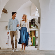 Coppia che passeggia sotto un passaggio ad archi bianco a Brixen Südtirol con borse per lo shopping.