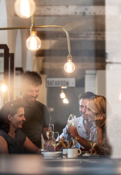Menschen essen gemeinsam in einem gemütlichen Restaurant in Brixen Südtirol, durch das Fenster gesehen | © IDM Südtirol-Alto Adige/Alex Filz