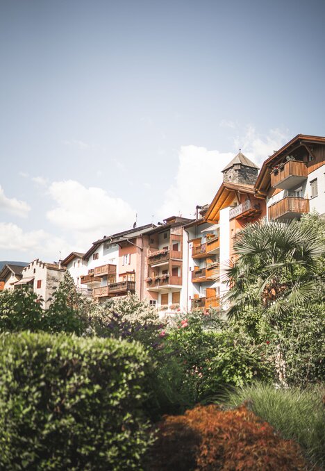 Case residenziali con balconi sopra il verde rigoglioso sotto un cielo luminoso.