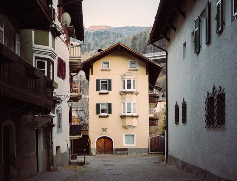 Narrow cobbled alley between traditional houses with mountains rising in the background in Brixen Südtirol.