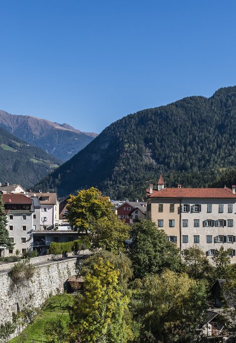 Centro storico di Brixen Südtirol con campanile, ponte e montagne sullo sfondo.