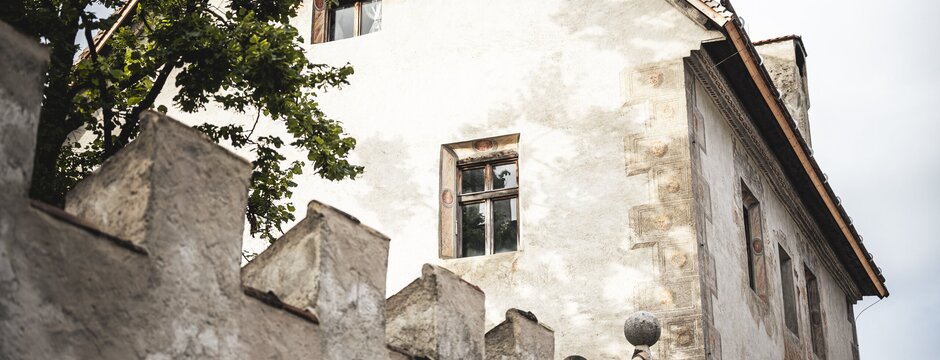 Antico edificio bianco con muri consumati e un albero accanto a Brixen Südtirol.