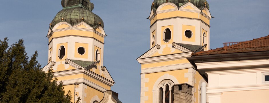Due campanili con cupole a cipolla si alzano sopra gli edifici storici sotto un cielo azzurro.