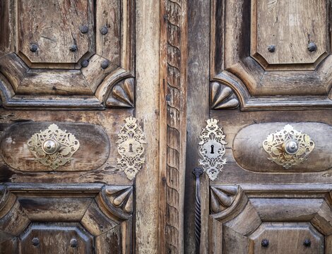 Ornate carved wooden double door with decorative metal locks and handles.