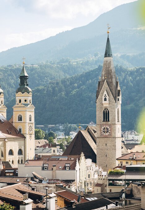 Historische Kirchtürme in Brixen Südtirol vor Bergflanken und sanfter Sommerstimmung.