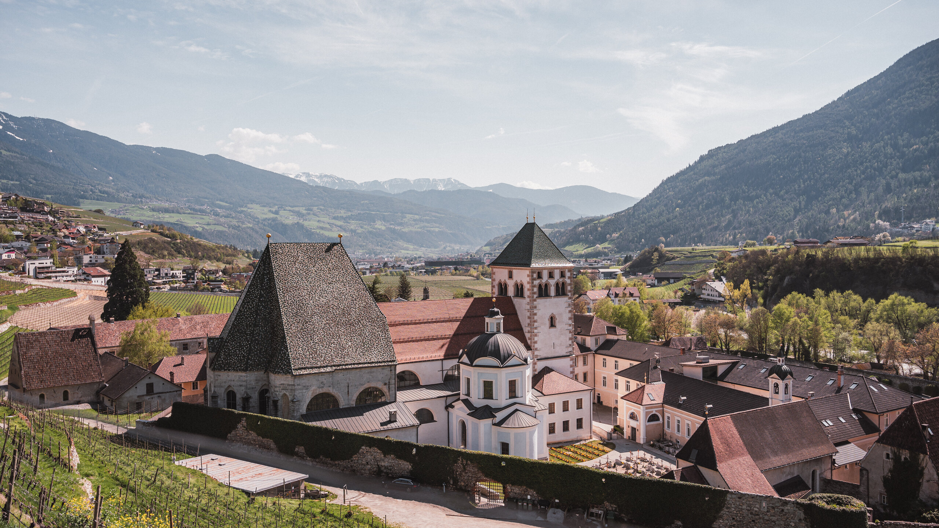 Historic abbey in Brixen Südtirol with vineyards, valley town and mountains in the background.