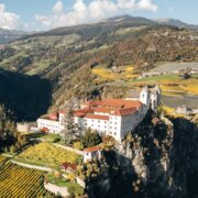 A monastery on a cliff above vineyards and a valley in Brixen Südtirol.