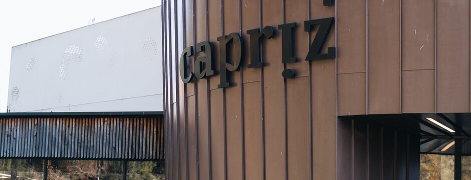 Esterno moderno dell’edificio capriz con prato in primo piano e insegna arancione pims.
