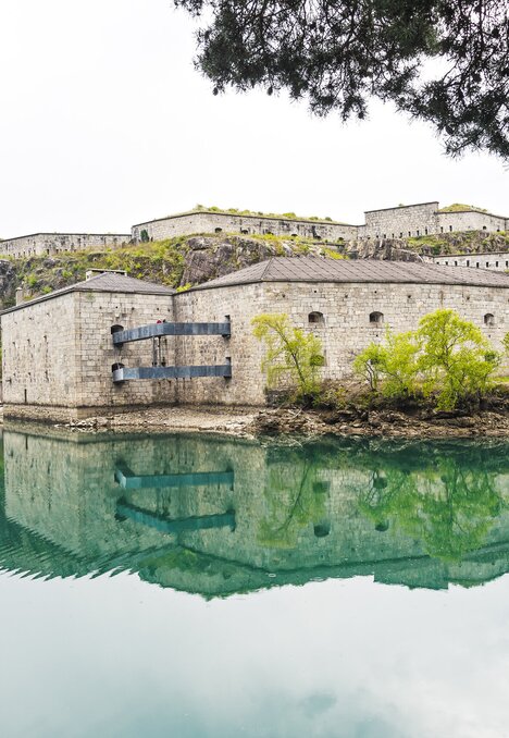 Forte in pietra riflesso in un lago di montagna tranquillo a Brixen Südtirol.