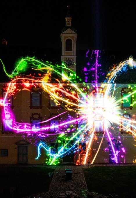Proiezione luminosa colorata sugli edifici storici del cortile di notte.