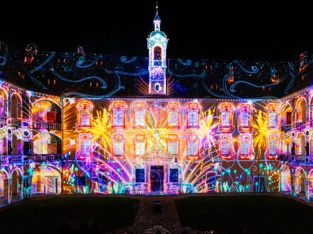 Proiezioni luminose colorate su un edificio storico del cortile di notte a Brixen Südtirol.