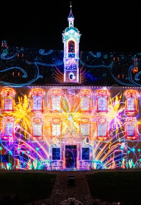 Bunte Lichtprojektionen auf einem historischen Hofgebäude bei Nacht in Brixen Südtirol.