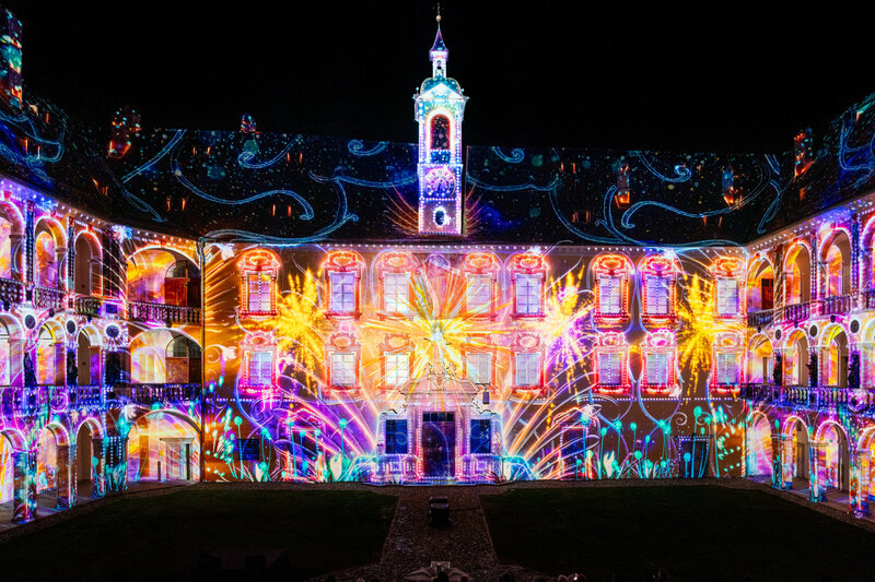 Bunte Lichtprojektionen auf einem historischen Hofgebäude bei Nacht in Brixen Südtirol.