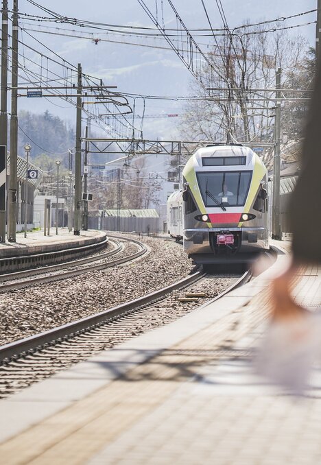 Train approaching the station platform in Brixen Südtirol on a bright day.