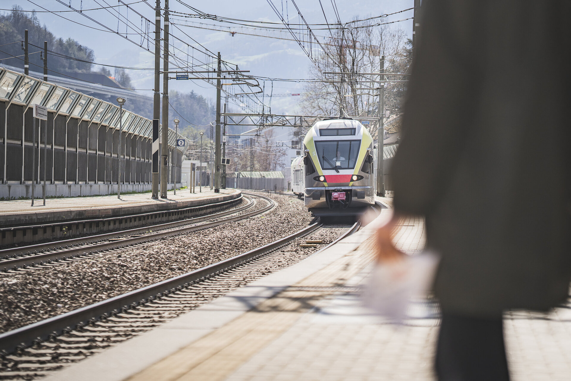 Treno in arrivo sul binario della stazione a Brixen Südtirol in una giornata luminosa.